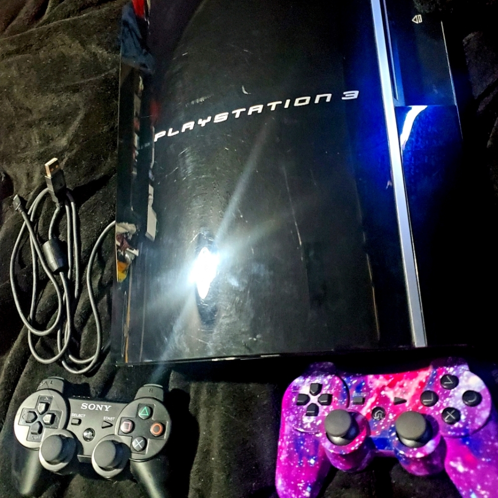 PlayStation 3 with two controllers and USB charging cord